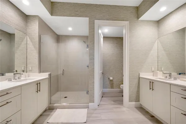 a bathroom with a double vanity sink a toilet and shower