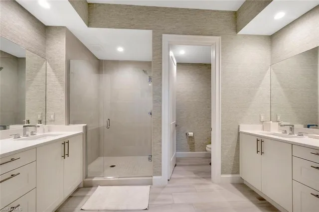 a bathroom with a double vanity sink a toilet and shower