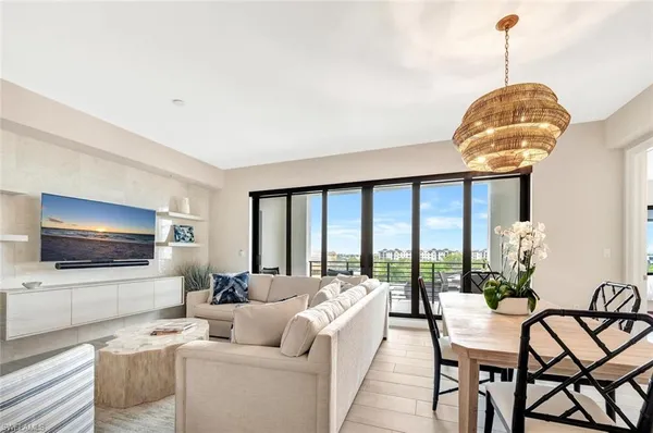 a living room with furniture a floor to ceiling window and flat screen tv
