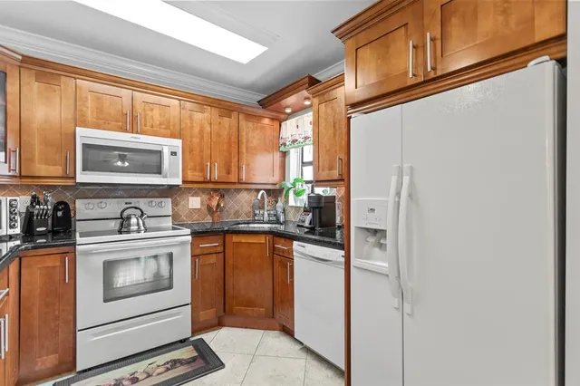 a dining room with stainless steel appliances a dining table and chairs with floor to ceiling window