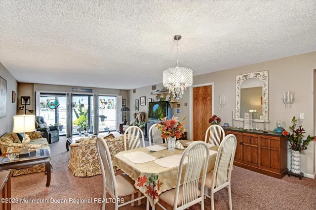 a view of a dining room with furniture a chandelier and a window