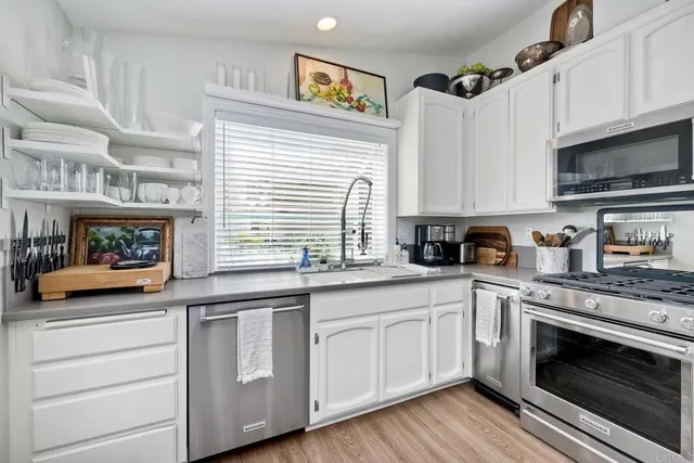 a kitchen with stainless steel appliances granite countertop a stove a sink and a microwave