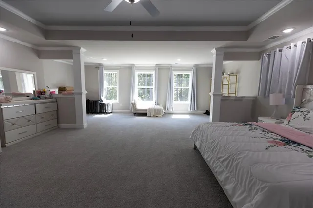 a spacious bedroom with a bed couch and windows