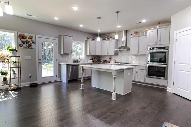 a kitchen with stainless steel appliances granite countertop a stove top oven a sink and a refrigerator