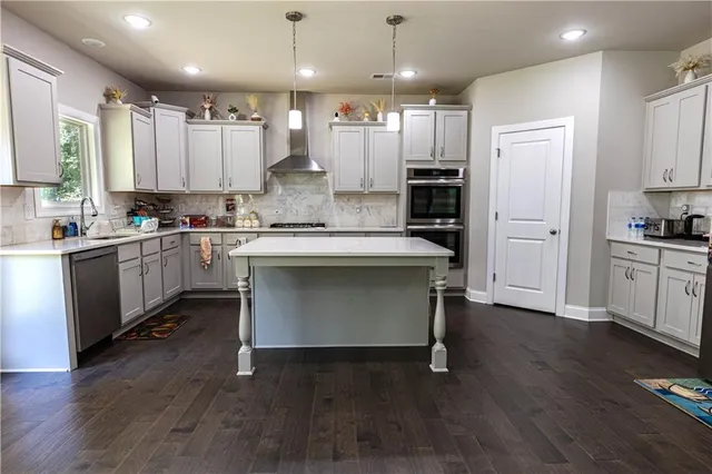 a kitchen with kitchen island granite countertop wooden floors stainless steel appliances and cabinets