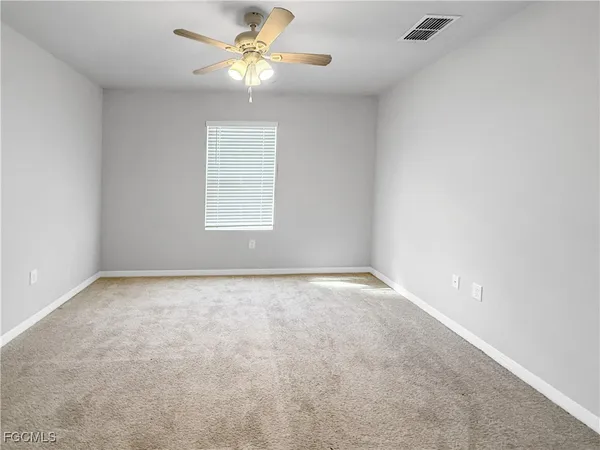 an empty room with a window and a ceiling fan
