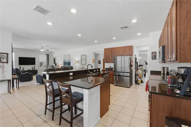 a kitchen with stainless steel appliances a sink a stove a refrigerator cabinets and a dining table