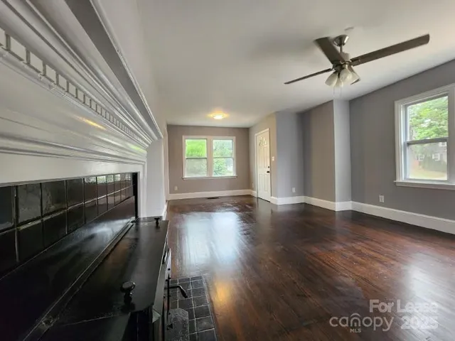 an empty room with wooden floor fan and windows