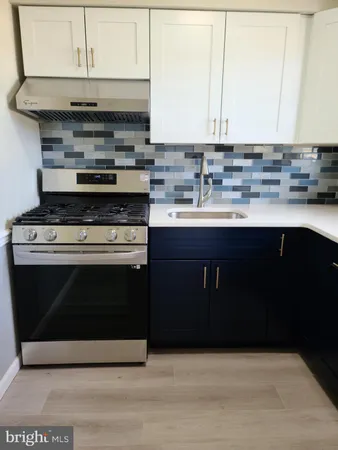 a kitchen with stainless steel appliances a stove a sink and white cabinets