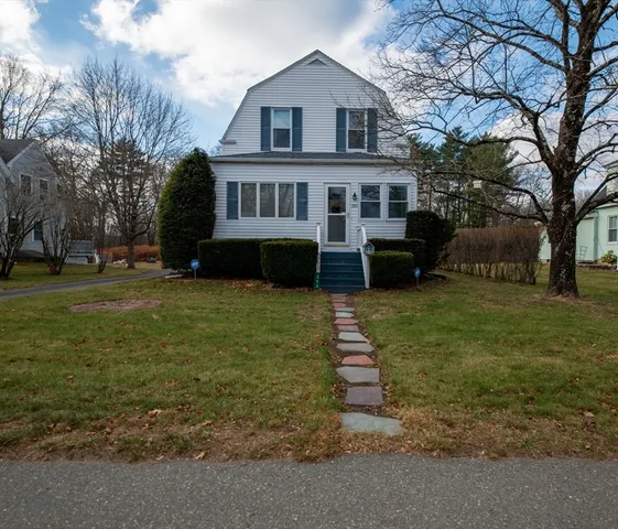 a front view of a house with a yard and trees