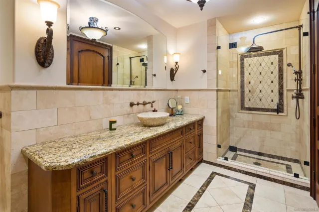 a bathroom with a granite countertop sink a mirror and shower