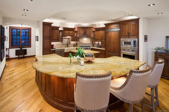 a dining room with stainless steel appliances kitchen island granite countertop a sink a microwave and chairs