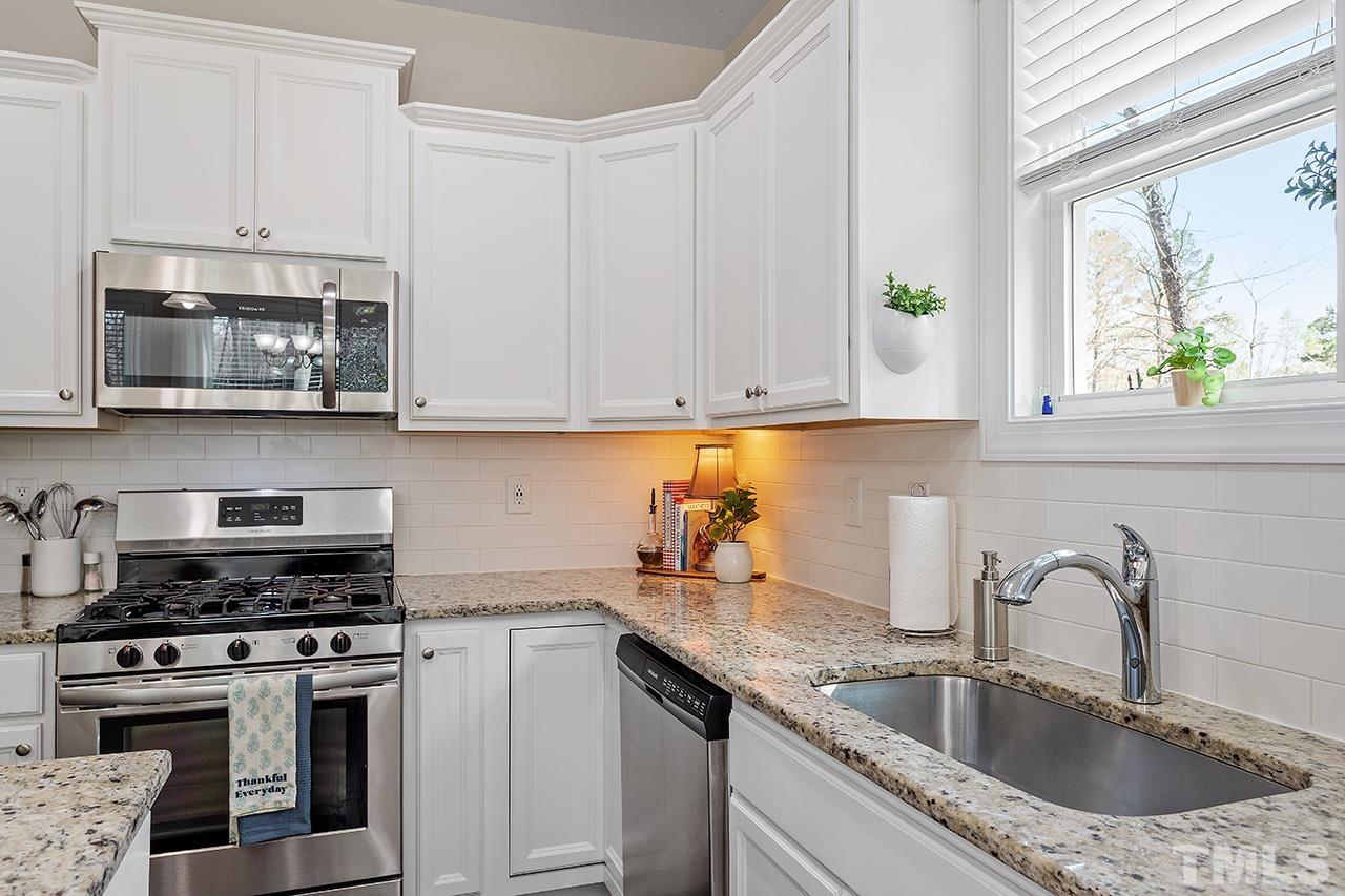 3622 Pine Needles Drive Wake Forest, NC 27587 - Photo 16 of 35 a kitchen with stainless steel appliances granite countertop a sink stove and microwave with wooden floor