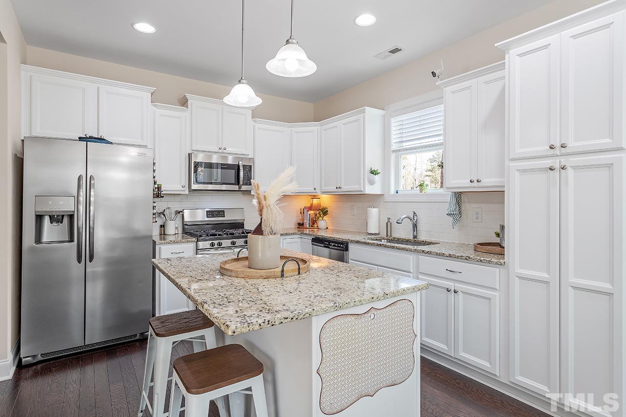 3622 Pine Needles Drive Wake Forest, NC 27587 - Photo 18 of 35 a kitchen with granite countertop a refrigerator a sink a stove a microwave and island with wooden floor