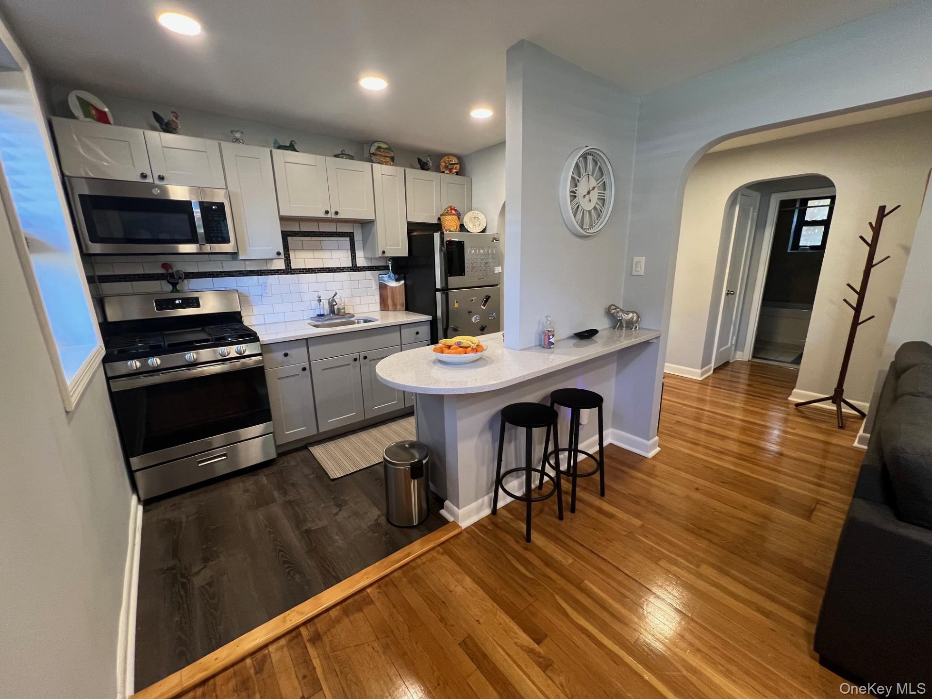 200 Richbell Road, Unit A2 Mamaroneck, NY 10543 - Photo 2 of 14 a kitchen with stainless steel appliances granite countertop a stove top oven a sink a dining table and chairs with wooden floor