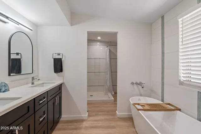 a bathroom with a tub a sink and mirror