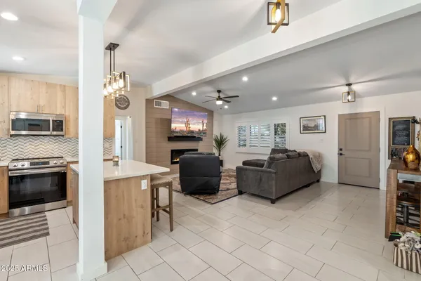 a living room with stainless steel appliances furniture a fireplace and a view of kitchen