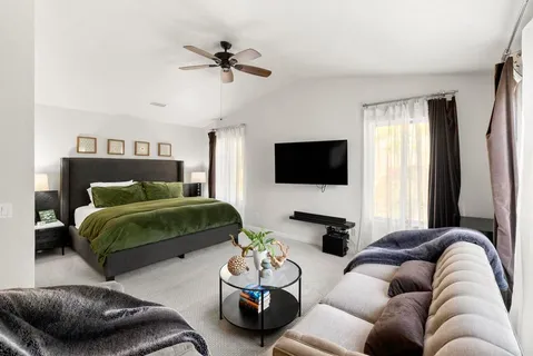 a bedroom with a bed a couch and a flat screen tv