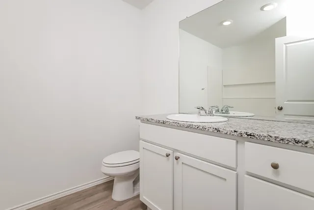 a bathroom with a granite countertop toilet a sink and a mirror
