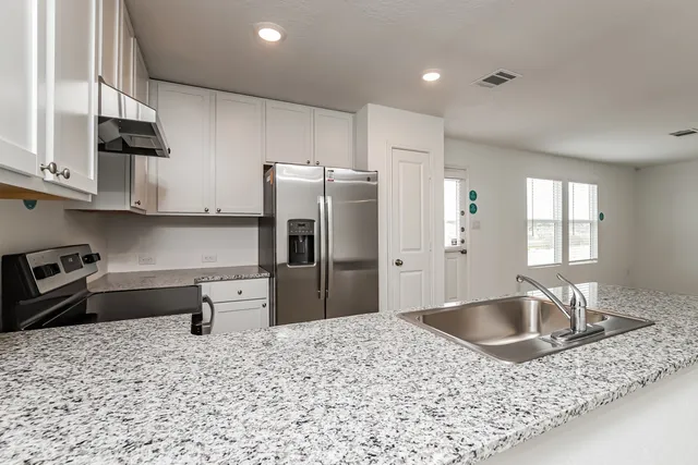 a kitchen with stainless steel appliances granite countertop a sink a stove and a refrigerator