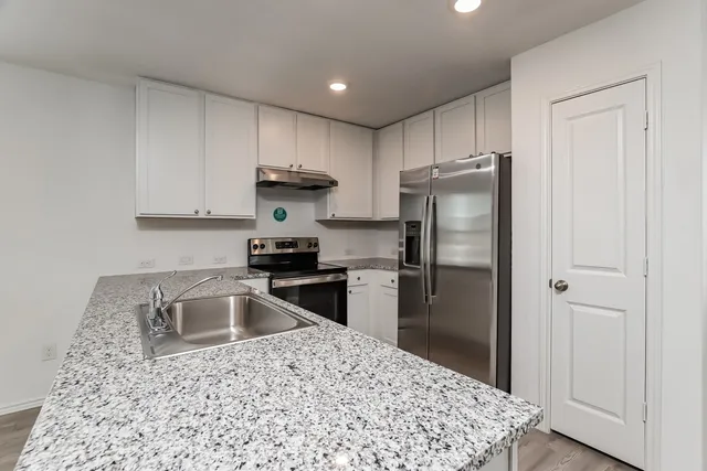 a kitchen with a refrigerator sink and cabinets