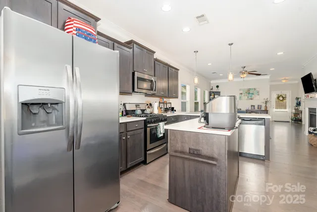 a kitchen with stainless steel appliances granite countertop a refrigerator a stove and a sink with wooden floor
