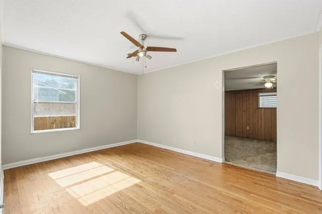 a view of empty room with wooden floor and fan