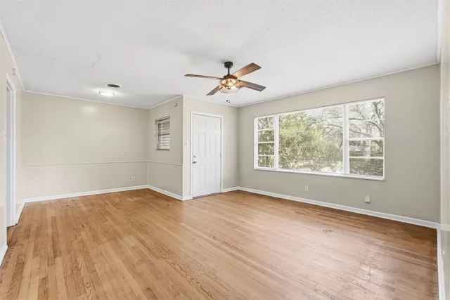 an empty room with wooden floor and windows