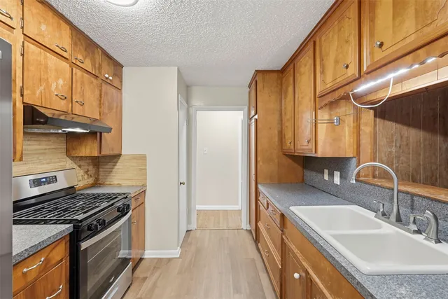 a kitchen with stainless steel appliances granite countertop a sink stove and refrigerator