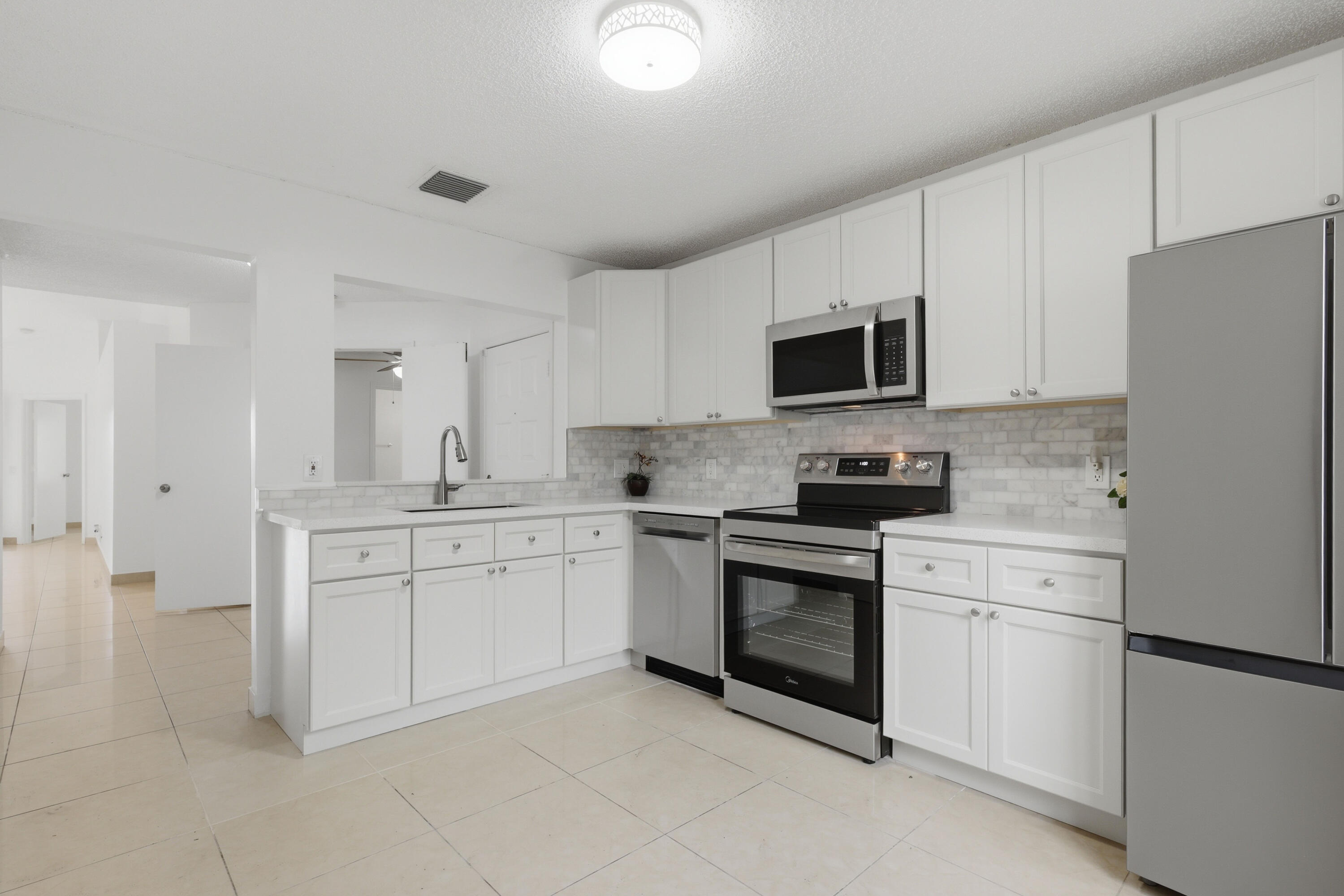 11697 Southwest 19th Street Miramar, FL 33025 - Photo 27 of 48 a kitchen with white cabinets and stainless steel appliances