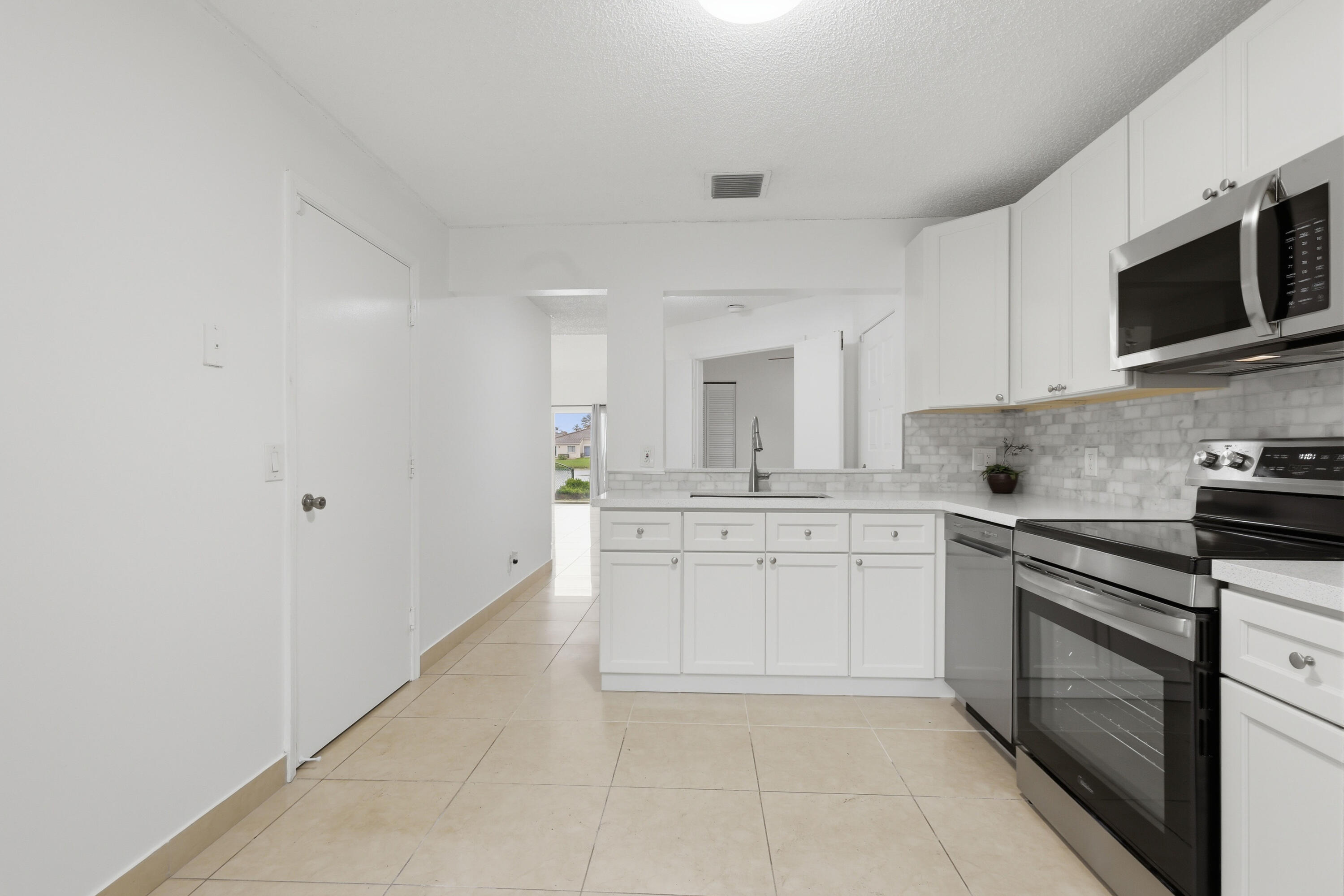 11697 Southwest 19th Street Miramar, FL 33025 - Photo 29 of 48 a kitchen with stainless steel appliances granite countertop a sink and dishwasher a stove top oven with white cabinets
