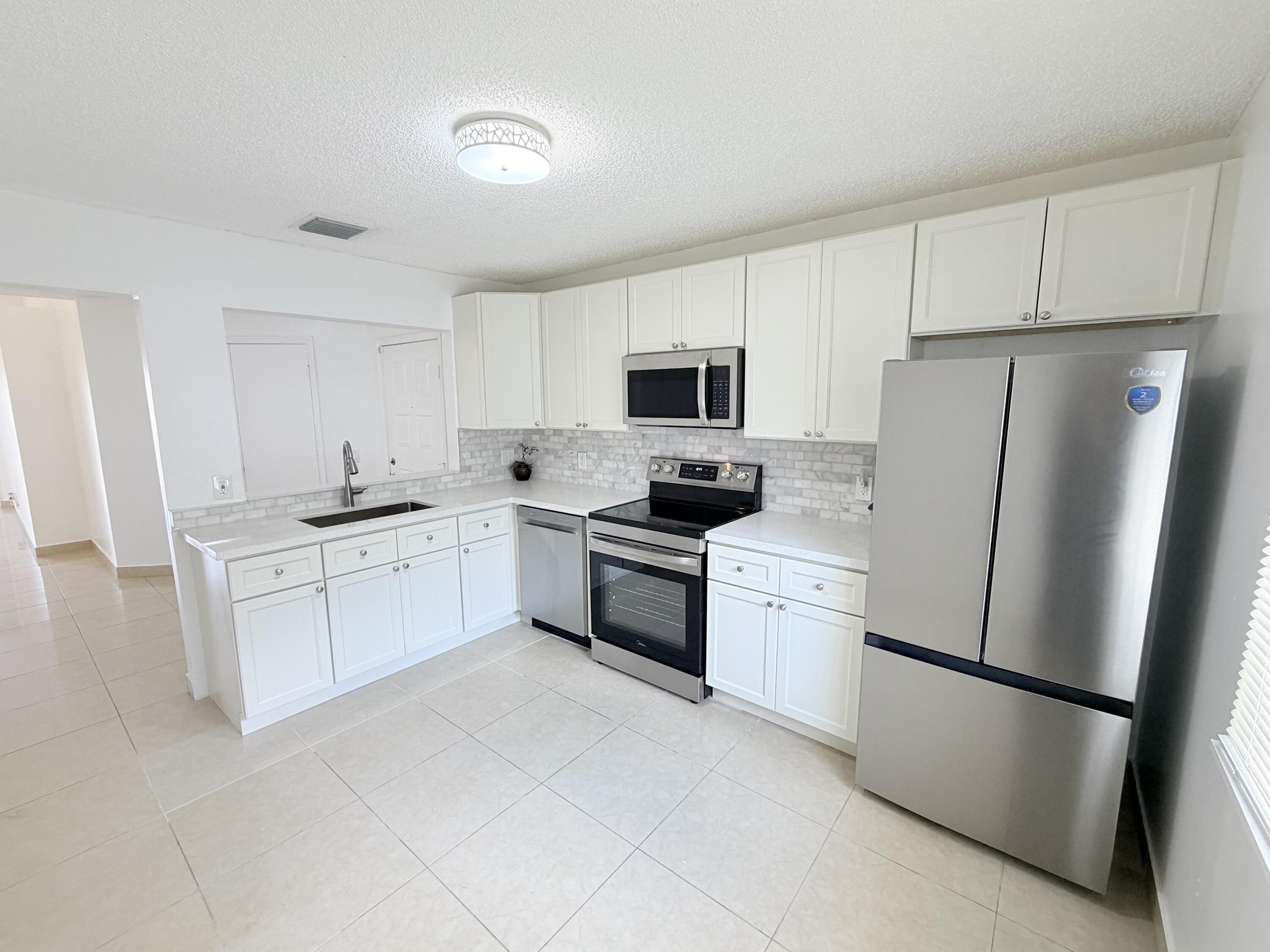 11697 Southwest 19th Street Miramar, FL 33025 - Photo 4 of 48 a kitchen with white cabinets and white appliances