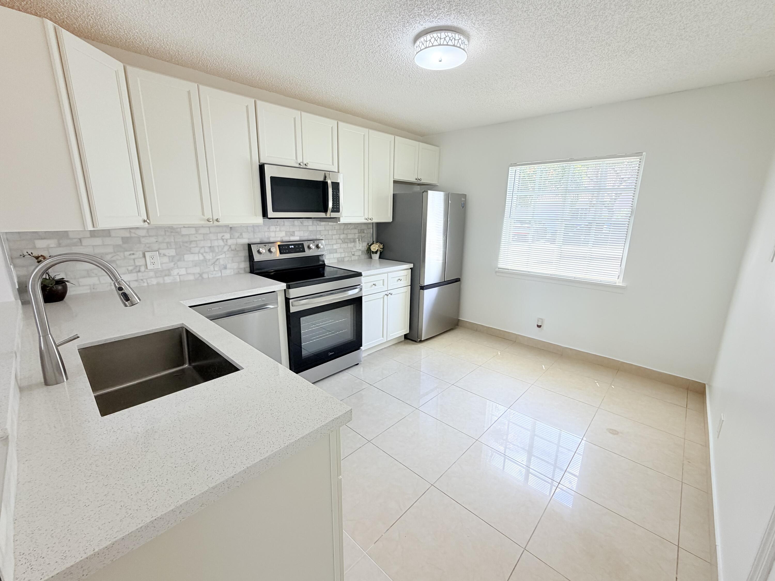 11697 Southwest 19th Street Miramar, FL 33025 - Photo 5 of 48 a kitchen with stainless steel appliances granite countertop a stove a sink and a microwave