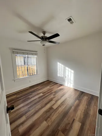 a view of an empty room with a window and wooden floor