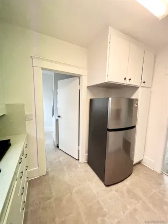 a view of kitchen with refrigerator and white cabinets