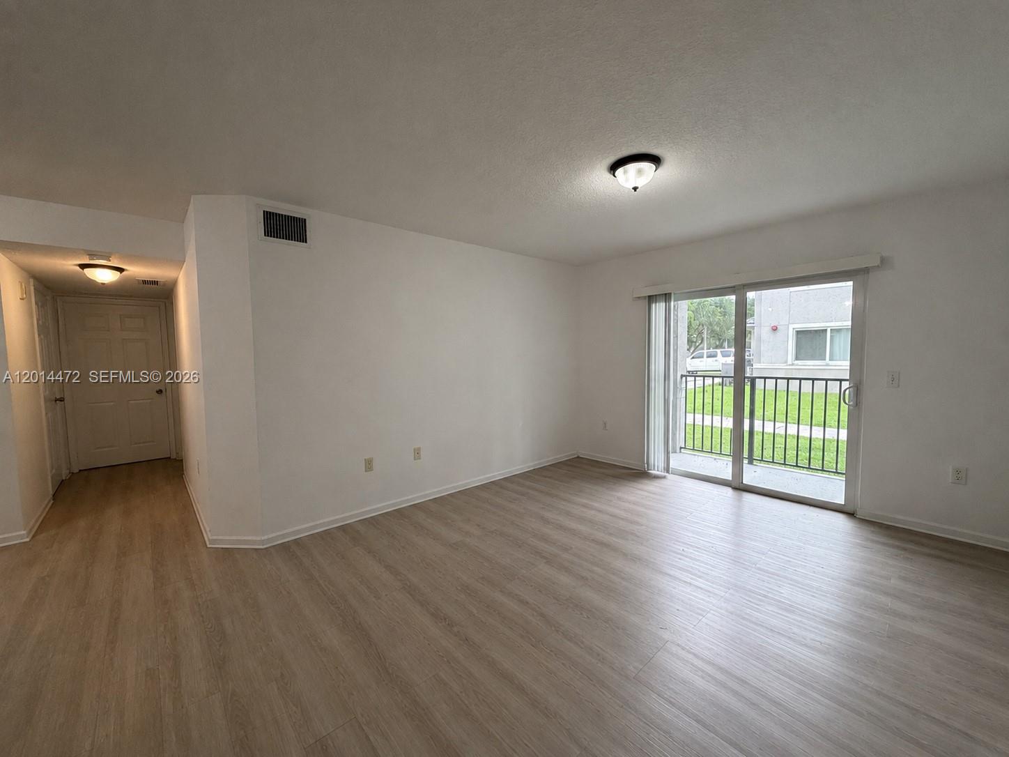 15410 Southwest 284th Street, Unit 8102 Homestead, FL 33033 - Photo 5 of 18 a view of an empty room with a window and wooden floor