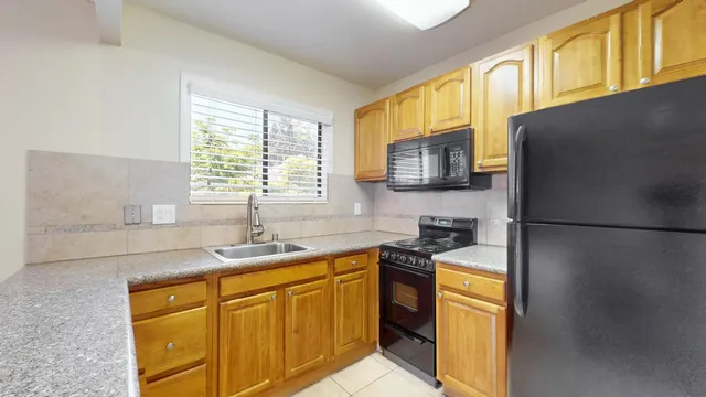 a kitchen with granite countertop a sink a stove and cabinets