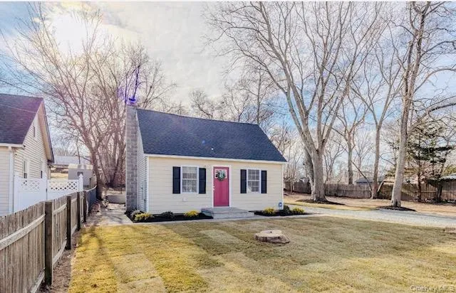 a view of a white house with a large tree next to a yard