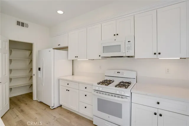 a kitchen with white cabinets and white appliances
