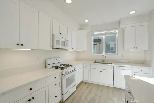 a kitchen with granite countertop white cabinets and white appliances