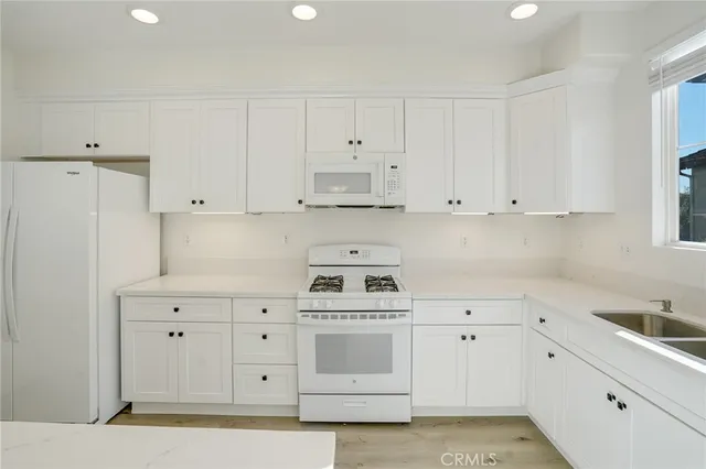 a kitchen with white cabinets and white appliances