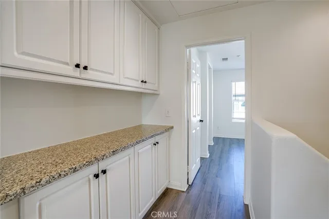 a kitchen with granite countertop white cabinets and a wooden floor