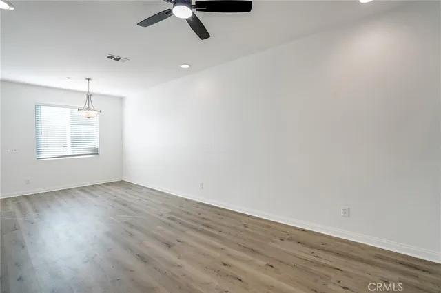 an empty room with wooden floor fan and windows
