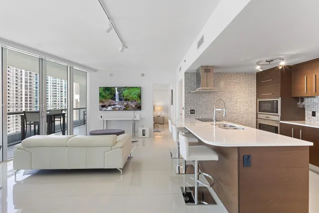 a living room with furniture a table and kitchen view