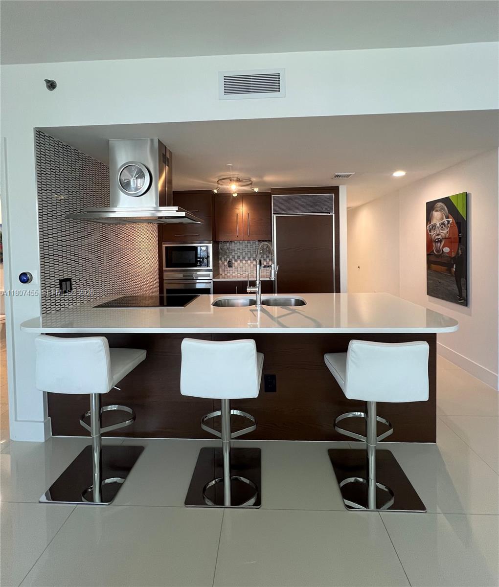 495 Brickell Avenue, Unit 2304 Miami, FL 33131 - Photo 7 of 29 a living room with stainless steel appliances kitchen island a table chairs and a refrigerator