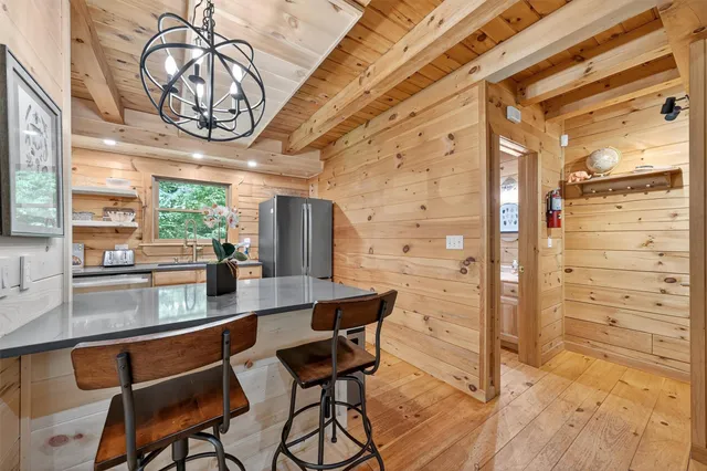 a kitchen with stainless steel appliances granite countertop a refrigerator a sink dishwasher a stove and white countertops with wooden floor