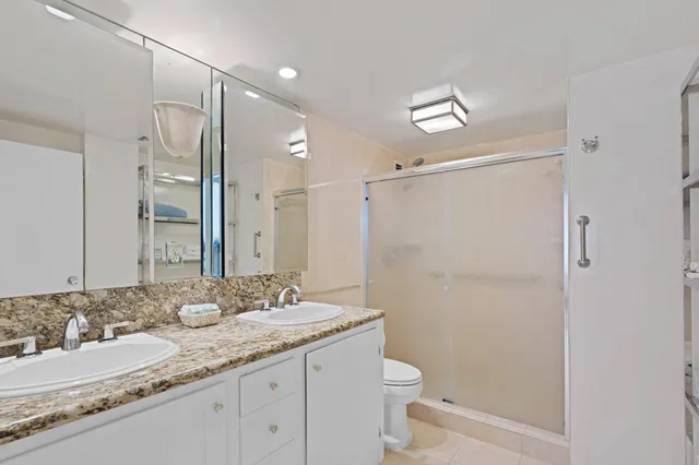 a bathroom with a granite countertop sink mirror vanity and toilet