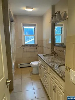 a bathroom with a granite countertop sink a toilet a mirror and bathtub