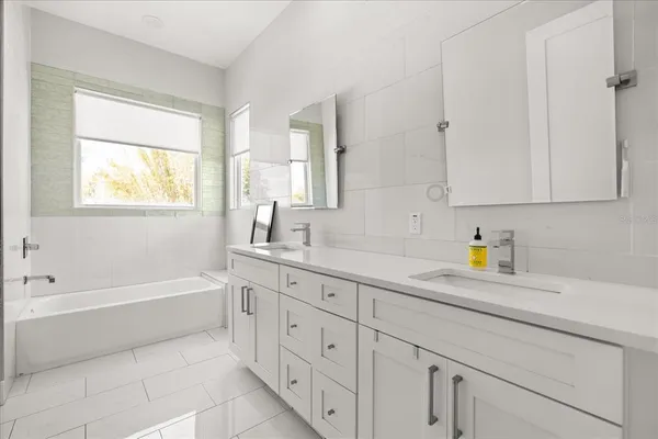 a spacious bathroom with a double vanity sink a mirror and a shower