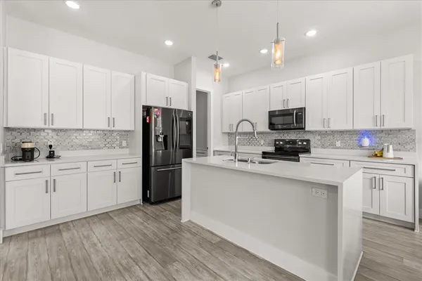 a kitchen with stainless steel appliances kitchen island granite countertop a refrigerator and microwave